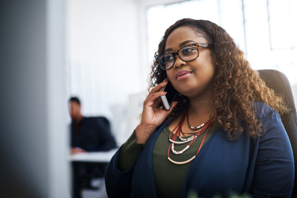 Shot of a young businesswoman using a mobile phone at her desk in a modern office