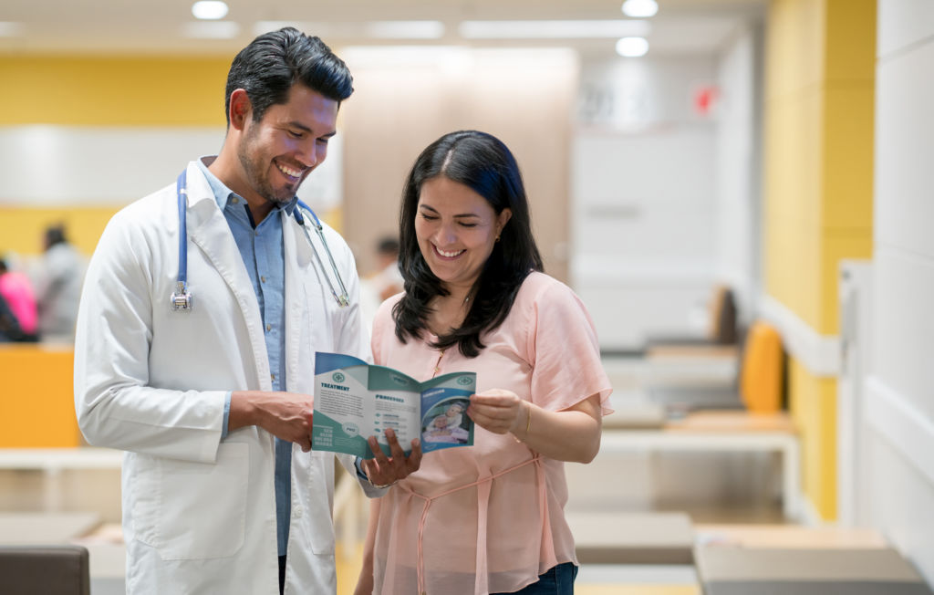 Cheerful woman talking to doctor about a retirement home for her parents while she looks at a brochure