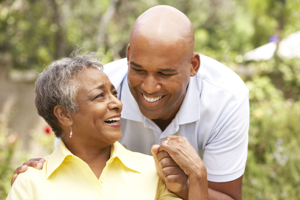 Senior Woman Being Hugged By Adult Son In Garden