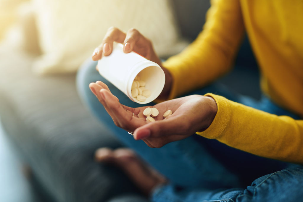 Cropped shot of a young woman taking medication at home