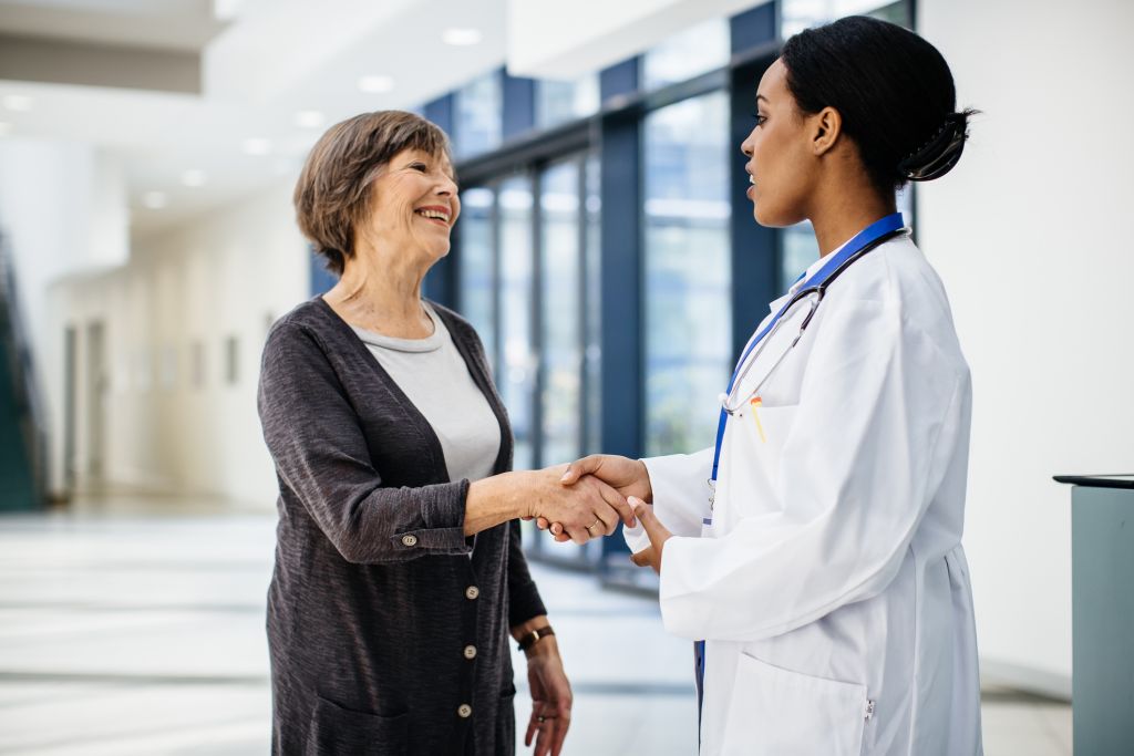 Female african doctor welcoming senior female patient in a hospital.